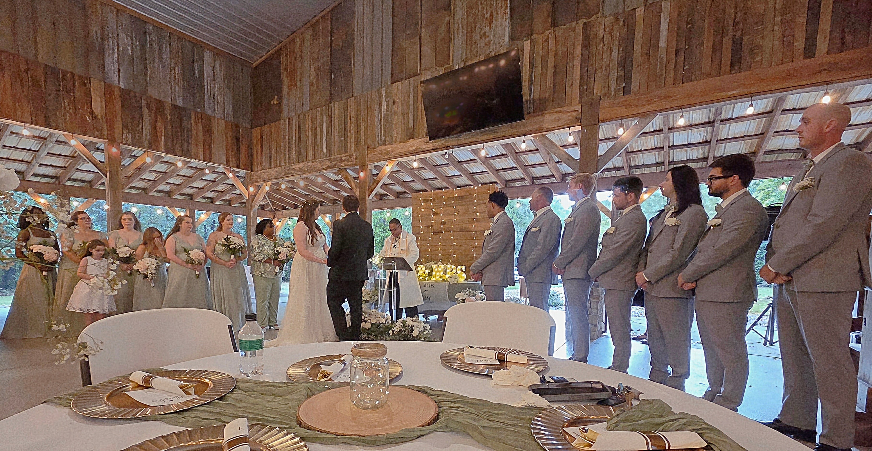 Wedding ceremony in rustic barn pavilion with full bridal party