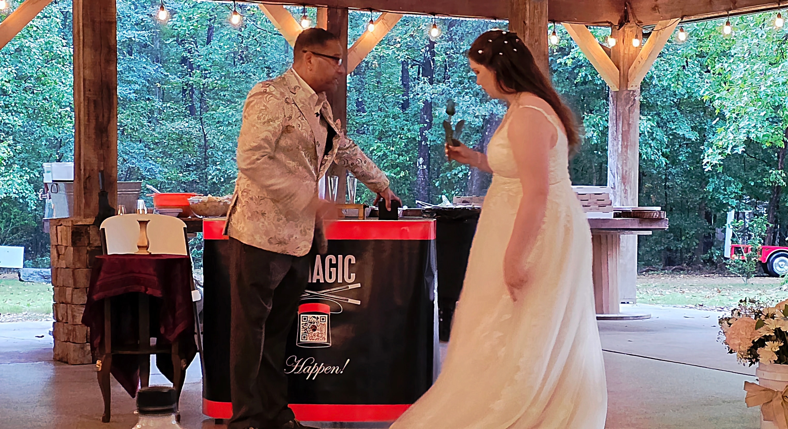 C. Magic performing magic trick with pink fan at outdoor pavilion wedding reception