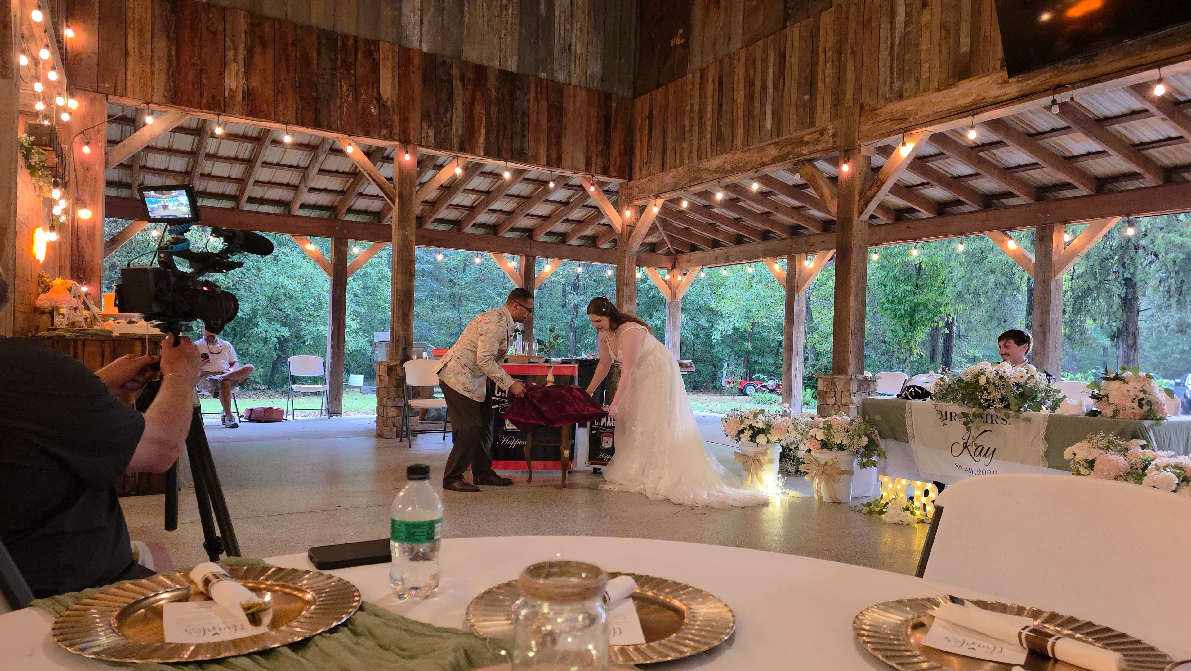 C. Magic performing tablecloth trick with bride filmed by videographer at Kay wedding