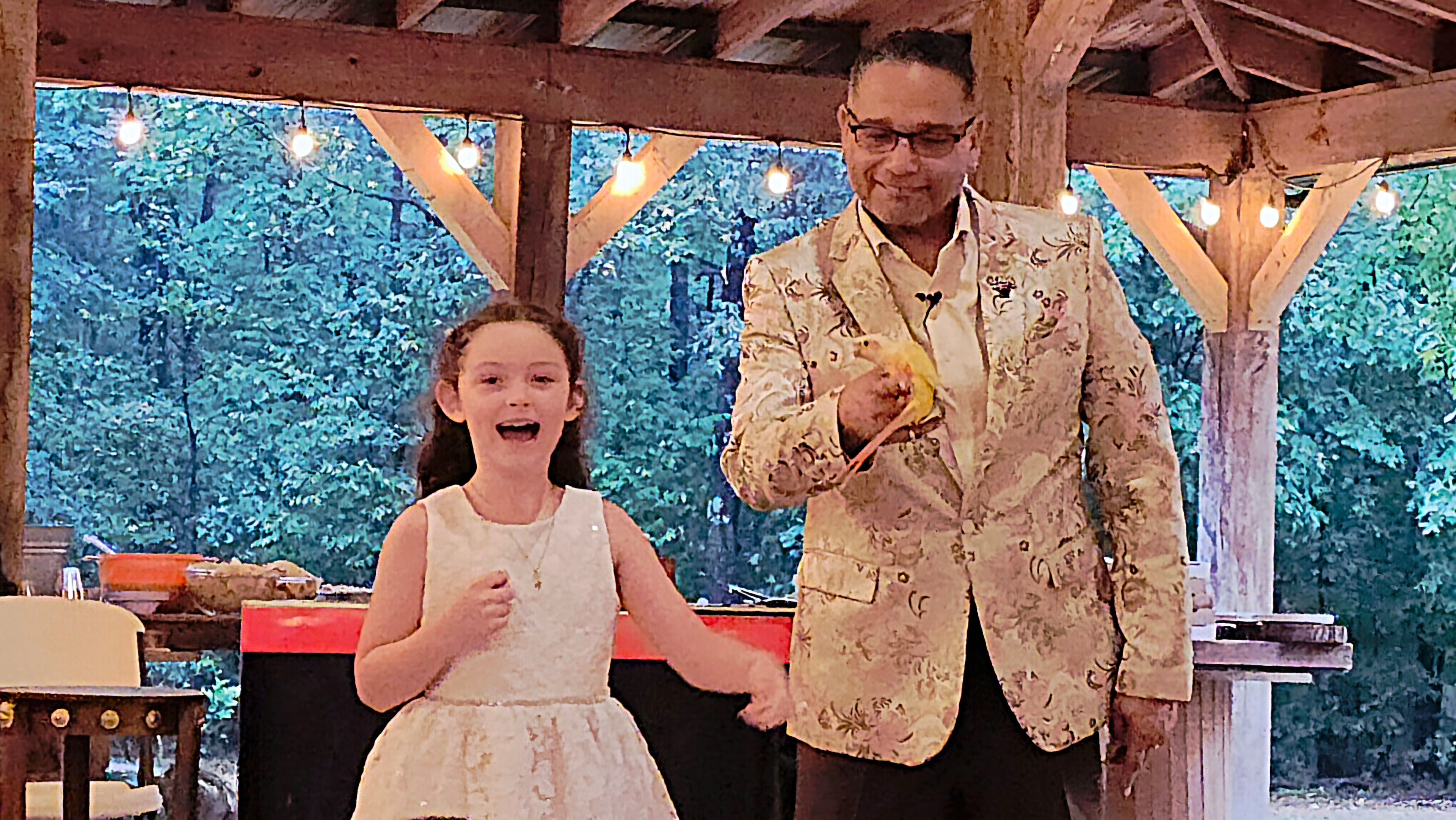Young girl delighted as C. Magic presents Starbust the Conure at outdoor pavilion wedding